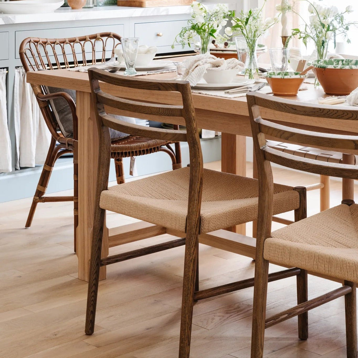 Glenmore Woven Dining Chairs and a Retro Rattan Dining Arm Chair at the oak kitchen table at Calimia Home