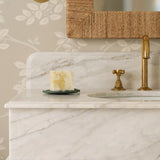 Calimia Home Golden Pollinator soap brick on a green dish, set on a white marble vanity with a brass faucet.
