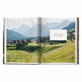 Calimia Home Great Escapes Alps book open to the Rote Wand spread showing a mountain village beneath alpine peaks.