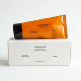 Frama Herbarium hand cream in an orange tube resting on its white product box against a plain background.