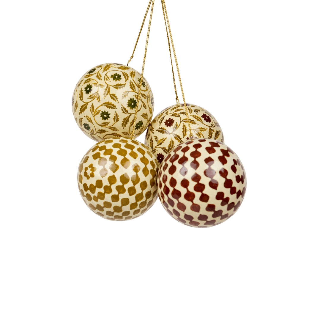Four Maison Poire hand-painted papier-mâché ornaments in the Marguerite and Agnes prints hanging together on gold cords