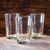 Calimia Home set of three hand-blown clear glass pint glasses with artisanal tapered design on a wooden surface