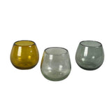 Calimia Home set of three rounded stemless glasses in amber, clear, and grey hand-blown recycled glass.