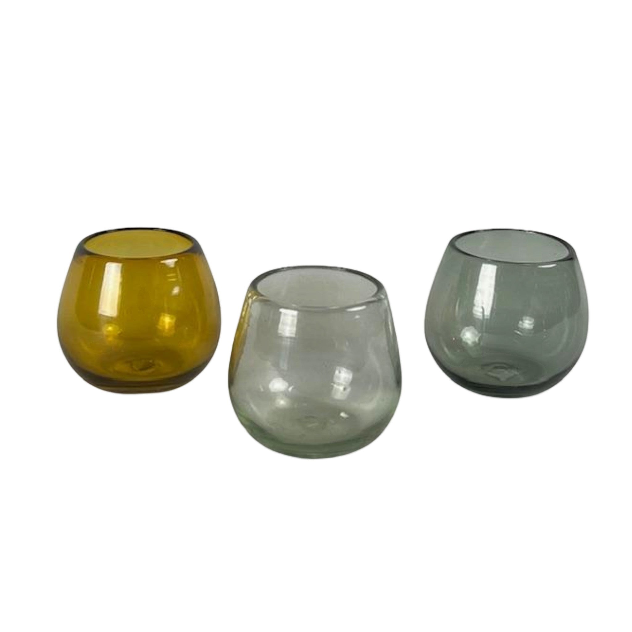 Calimia Home set of three rounded stemless glasses in amber, clear, and grey hand-blown recycled glass.