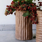 Calimia Home handmade terracotta cement vase with a textured, ribbed surface holding a branch of fresh blackberries.