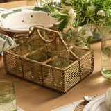 Calimia Home handwoven rattan and bamboo glassware holder with six compartments and a central handle on a dining table