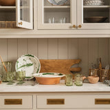 Calimia Home hand-blown olive recycled glass pitcher with etched thistle design displayed on a kitchen counter.