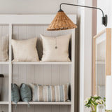 Calimia Home Iris mustard and taupe hand-embroidered hemp pillow with rosette motif on a white wooden shelf