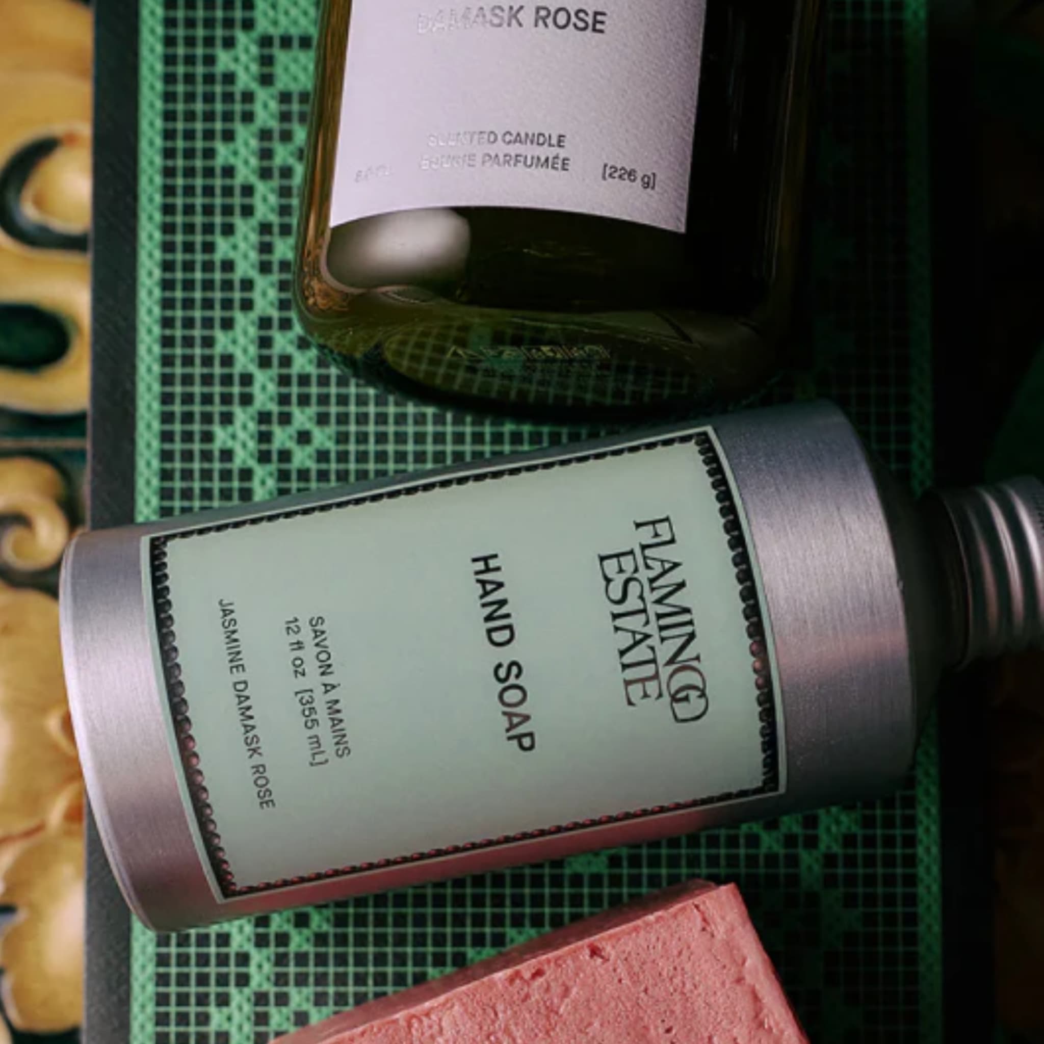 Detail view of the three-piece Jasmine Damask Rose Bath Set showing labels and textures of hand soap, candle, and soap brick