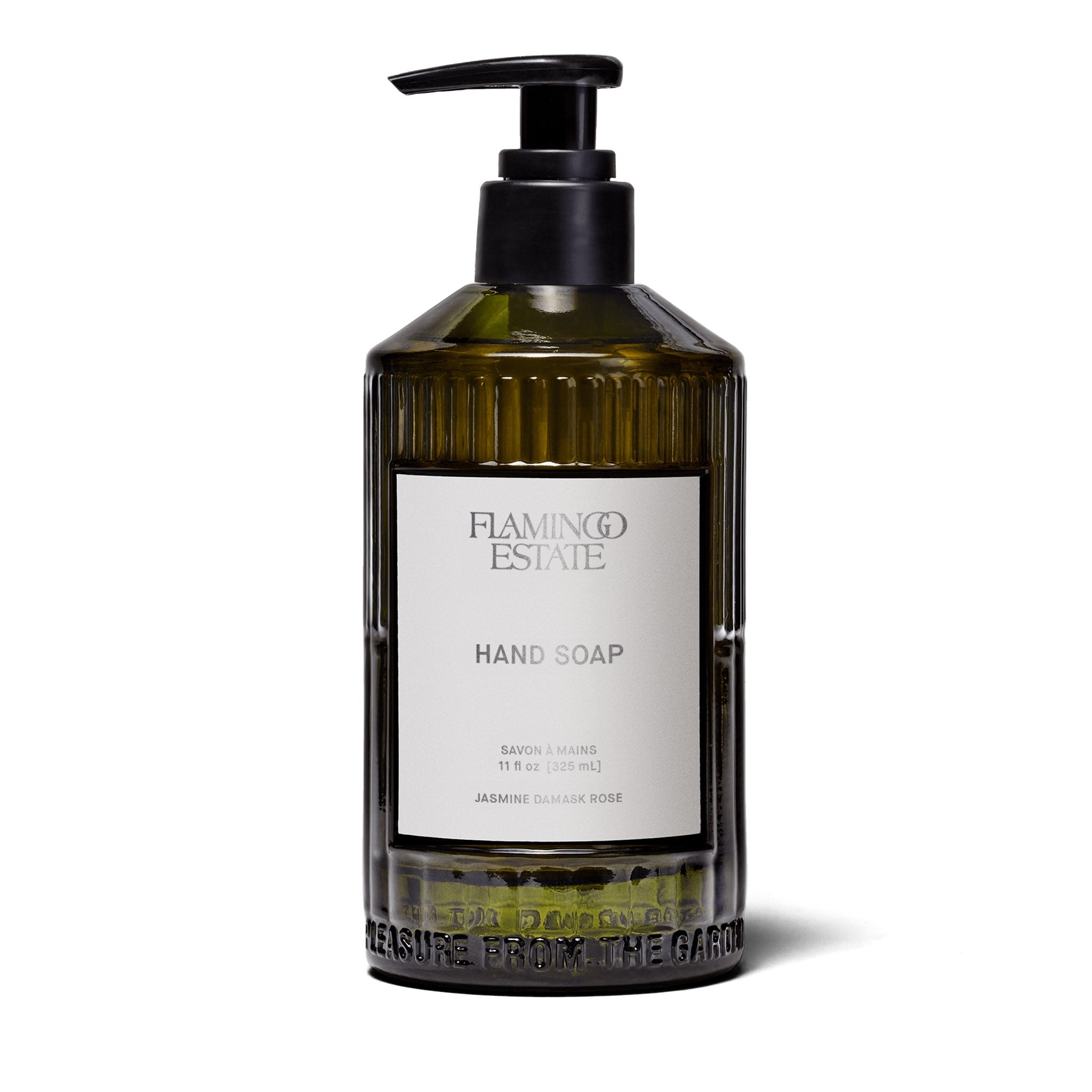 A fluted forest-green glass bottle of Flamingo Estate Jasmine Damask Rose Hand Soap with a white label, on a white background.