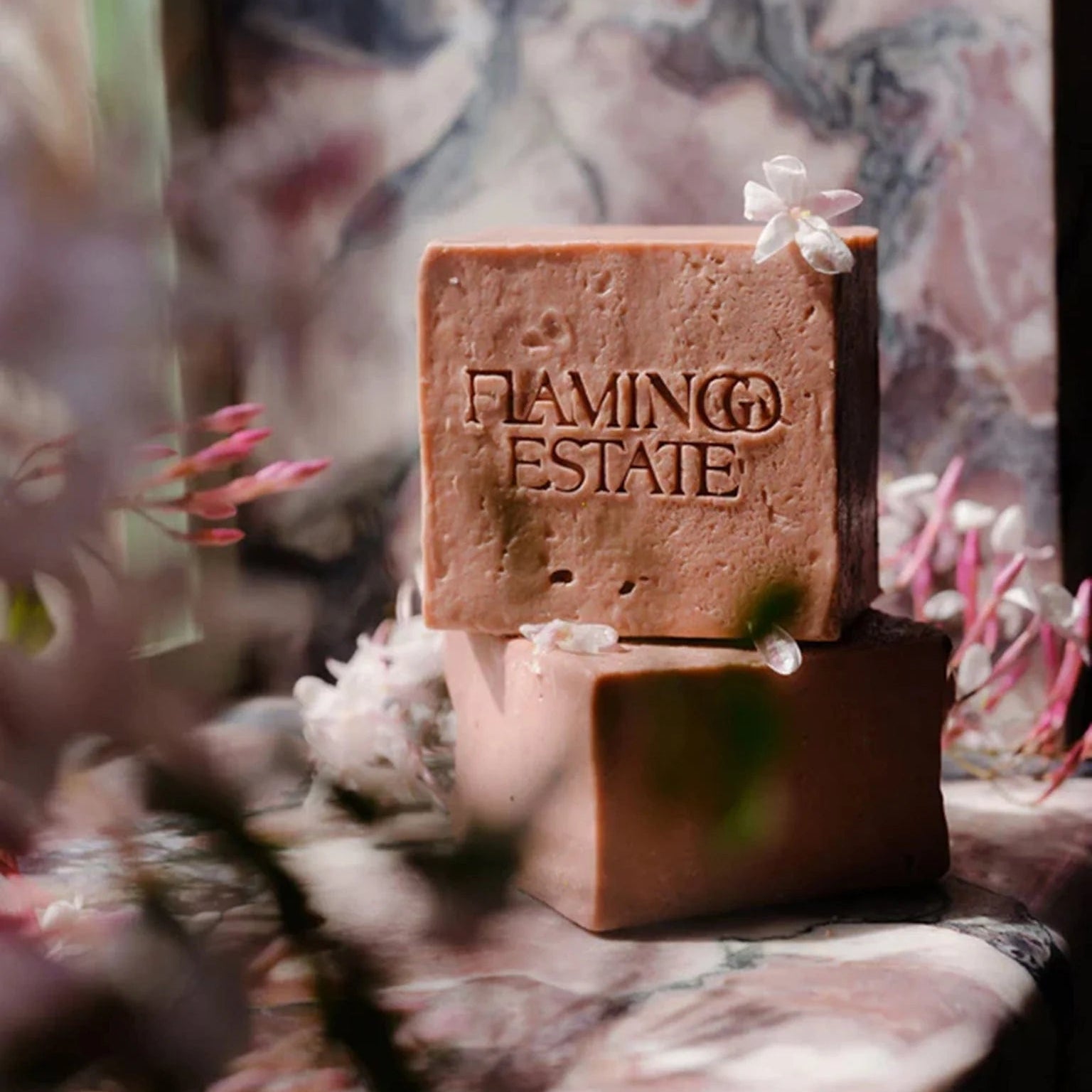 Two soap bars with 'Flamingo Estate' branding on a floral background