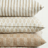 Walter G Kythira Washed Pista pillows stacked with striped, floral, and geometric patterns in neutral tones.