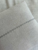 Close-up detail of the Lea Pillow showing the hand-embroidered line pattern on natural beige Belgian linen