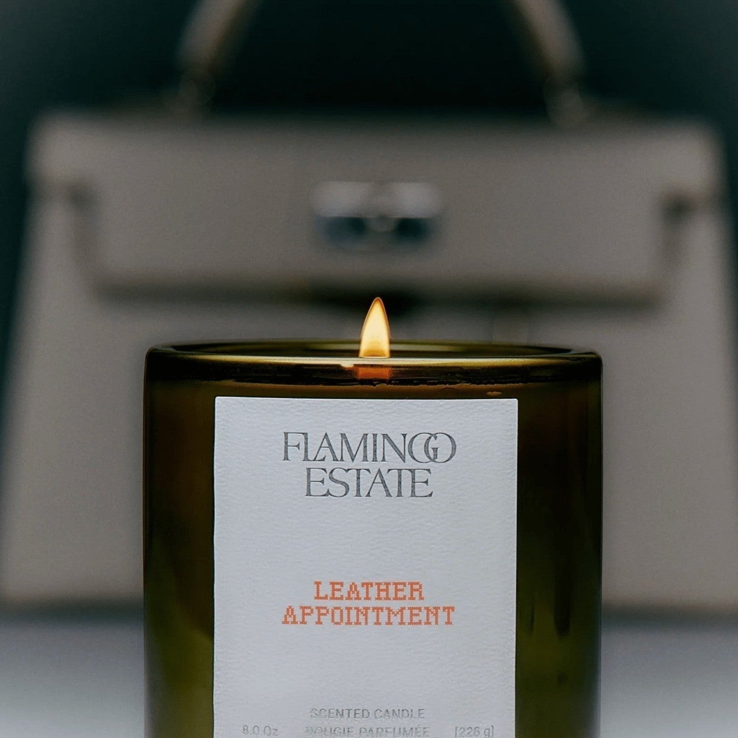 Flamingo Estate Leather Appointment scented candle in a fluted forest-green glass vessel with lit wick