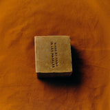 Flamingo Estate Manuka honey soap brick with Made by Hand in Los Angeles embossed on a textured amber surface.