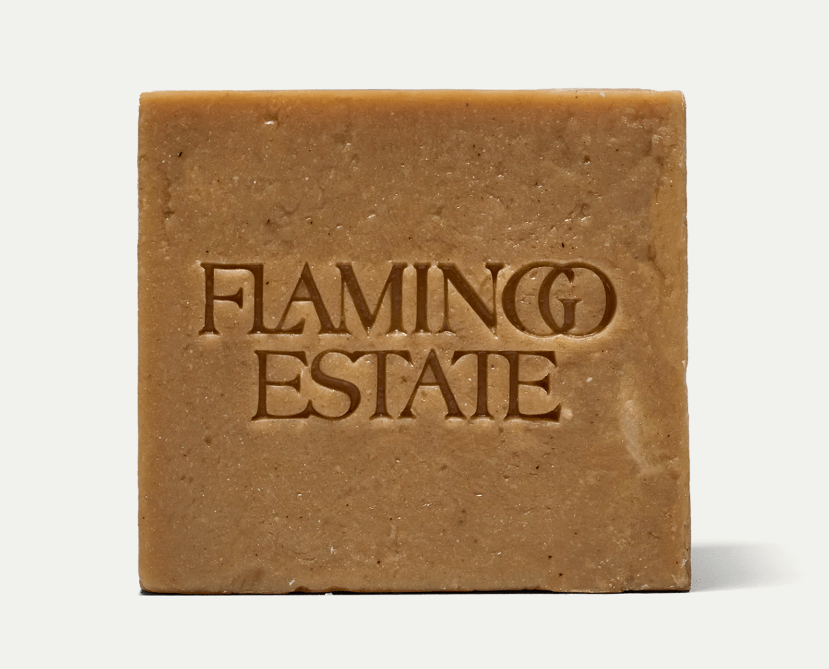 The honey-toned, golden-tan Manuka Honey Soap Brick from Flamingo Estate, embossed with the brand wordmark, photographed on a soft cream background.