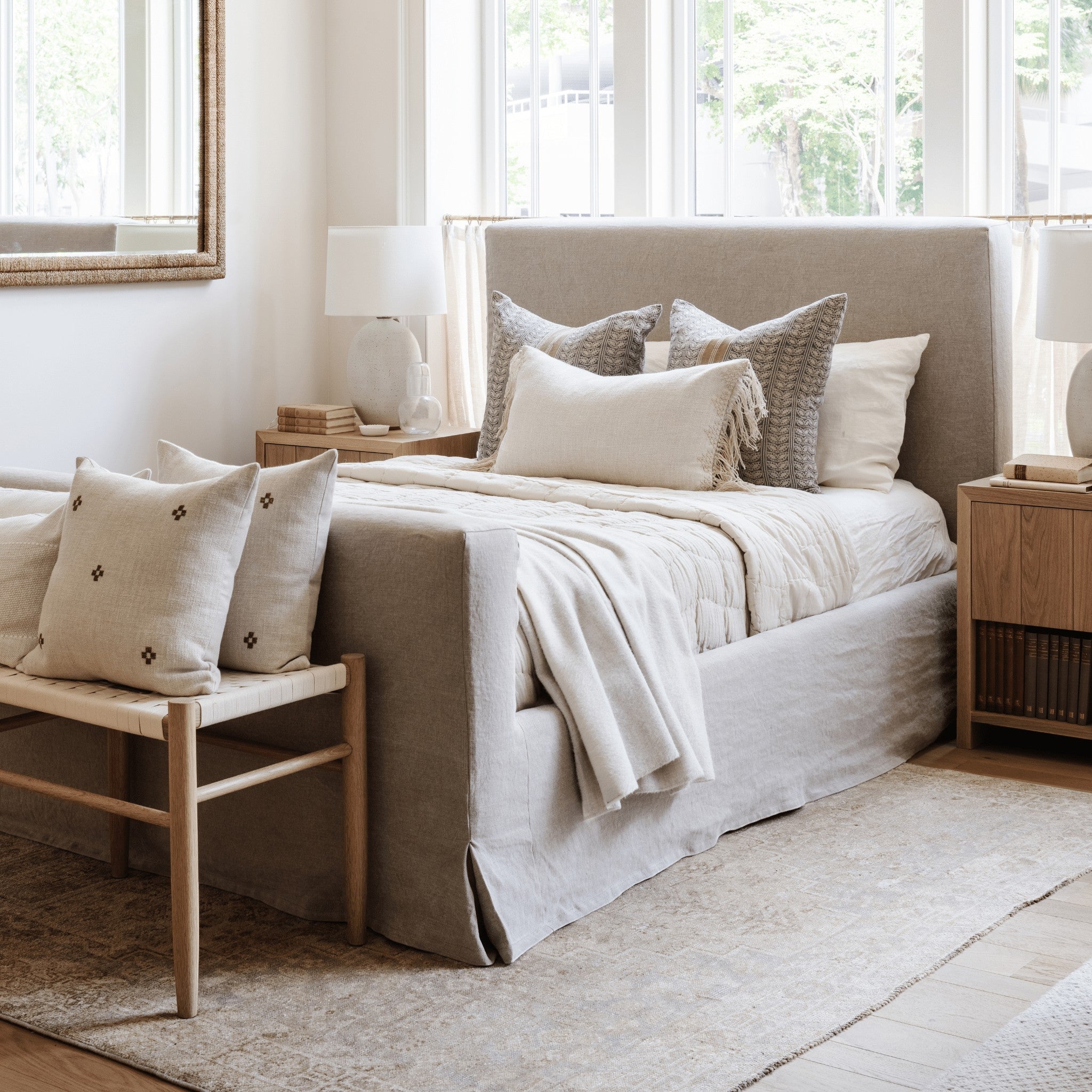 Calimia Home Mara Bed featuring a beige slipcovered frame with layered neutral pillows and a matching bench in a bedroom