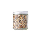 Calicutts Montreal spice blend in a clear glass jar with a silver lid, featuring coarse garlic, peppercorn, and dill.