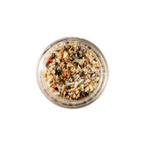 Calicutts Montreal spice blend in a glass jar, featuring sea salt, black peppercorns, garlic, onion, and dill seeds.
