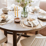 Talah Home natural straw flower napkin ring on a beige linen napkin in a rustic dining table setting