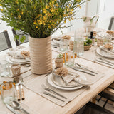 Talah Home natural straw flower napkin ring on a rustic table setting with linen napkins and yellow floral centerpiece