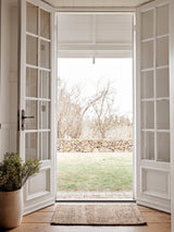 Armadillo Nest Nook Rug in Natural, a second view of the handwoven jute flatweave rug in a styled interior