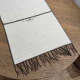 Noa Table Runner detail showing hand-embroidered chocolate-tone motif on natural cream linen