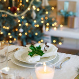 Pom Pom At Home ivory linen-cotton blend placemats with frayed edges set on a festive holiday table with dinnerware.