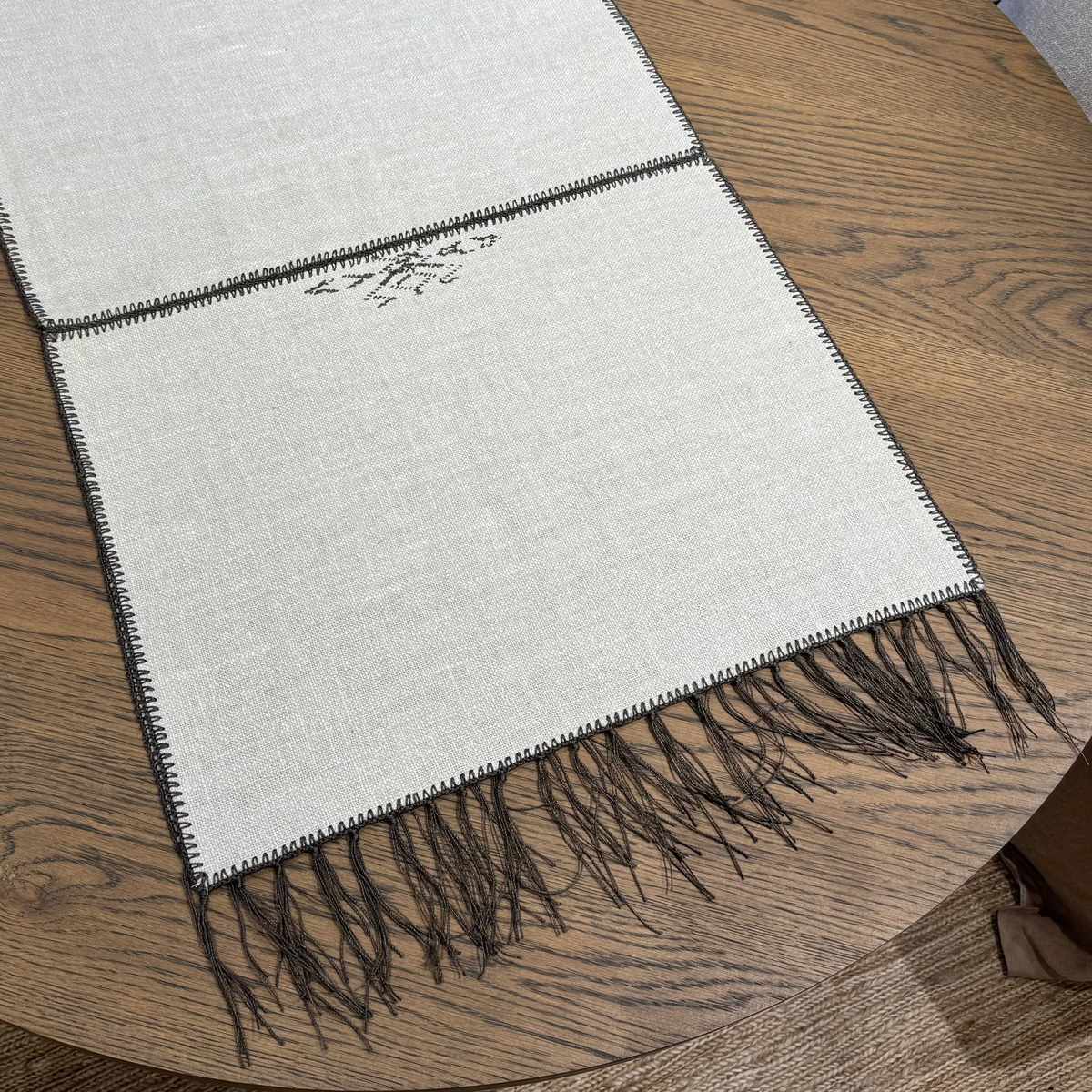 Noa Table Runner detail showing hand-embroidered chocolate-tone motif on natural cream linen