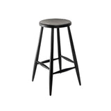 Calimia Home Omah stool in black stained wood with a round seat, tapered legs, and integrated footrests.