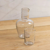 Be Home Pebble Glass Bedside Carafe set with a textured clear glass pitcher and matching tumbler on wood table.