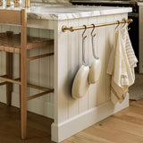 Sir Madam Porto Linens tea towels in dune with brown stripes hanging on a brass rail in a modern kitchen