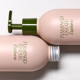 Two cream Flamingo Estate Euphoria refill bottles lie on their sides on a pale surface, one capped silver, the other showing the green pump dispenser.
