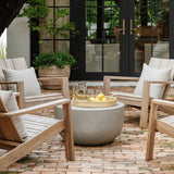 Calimia Home ribbed terracotta belly pot holding a small tree on a brick patio with wooden chairs