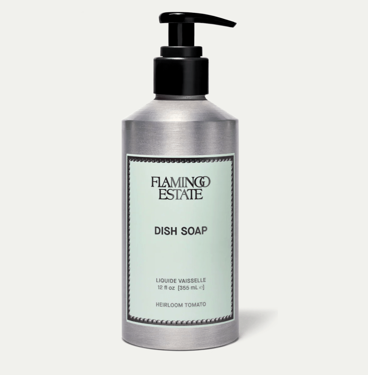 A brushed aluminum Flamingo Estate Heirloom Tomato Dish Soap pump bottle with sage-green label sits centered on a soft cream background.