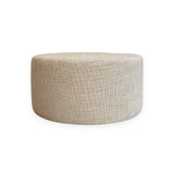 Calimia Home round ottoman upholstered in textured beige Belgian linen with a minimalist silhouette.