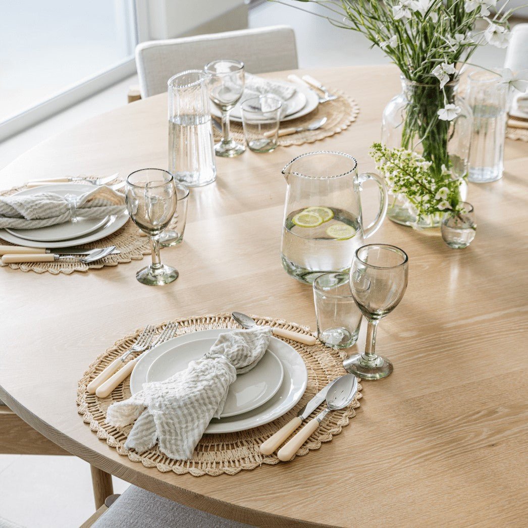 Be Home Ruffle Glass Pitcher filled with water and lemon slices on a beautifully set wooden dining table.