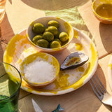 Il Buco Fiore di Sale finishing salt in a small yellow-splattered ceramic bowl served with olives on a plate
