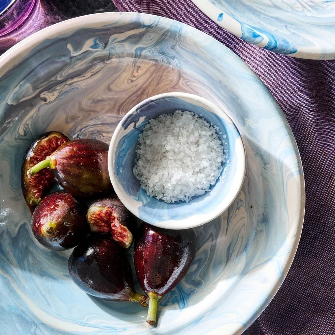 Il Buco Sale Grosso coarse Italian sea salt in a small blue marbled bowl with fresh figs on a purple cloth