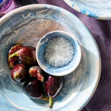 Il Buco Sale Grosso coarse Italian sea salt in a small blue marbled bowl with fresh figs on a purple cloth