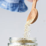Calicutts salt and pepper spice blend being poured from a wooden spoon into a glass jar