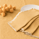 Close up of the ivory scalloped edge and contrast stitching on mustard cotton linen napkins