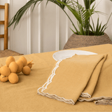 Mustard scalloped napkins folded beside a white plate on a mustard tablecloth