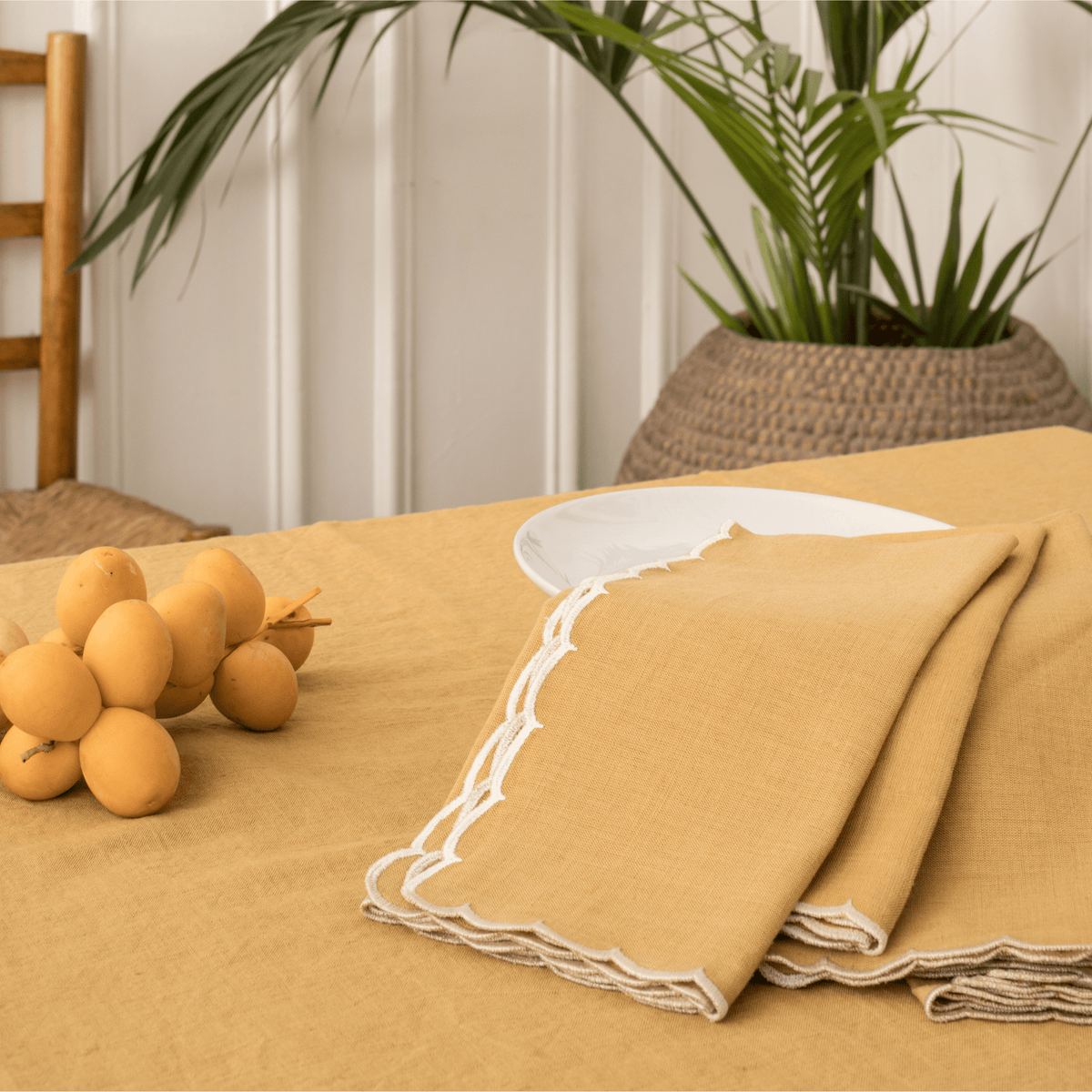 Mustard scalloped napkins folded beside a white plate on a mustard tablecloth