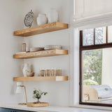 Calimia Home glass tumblers with hand-woven natural seagrass sleeves displayed on wooden kitchen shelves