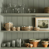 Be Home seagrass cage bowl with glass insert displayed on a sage green shelf with other kitchenware.