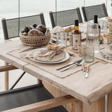 Be Home Seagrass Cage Bowl filled with eggplants on a rustic wooden dining table with linen place settings.