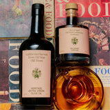 Overhead shot of the Flamingo Estate olive oil and balsamic vinegar atop vintage Wine & Food magazines, a glass teacup of golden liquid resting beside them.