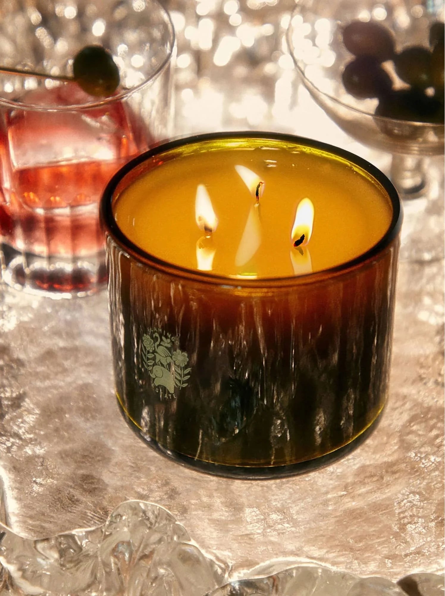 Lit Jasmine Damask Rose XL candle with all three wicks burning, casting warm light across a styled interior scene