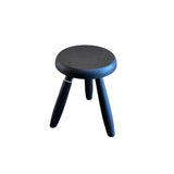 Calimia Home Tori stool in black wood with three tapered legs and a round seat finished in natural hand-rubbed varnish.